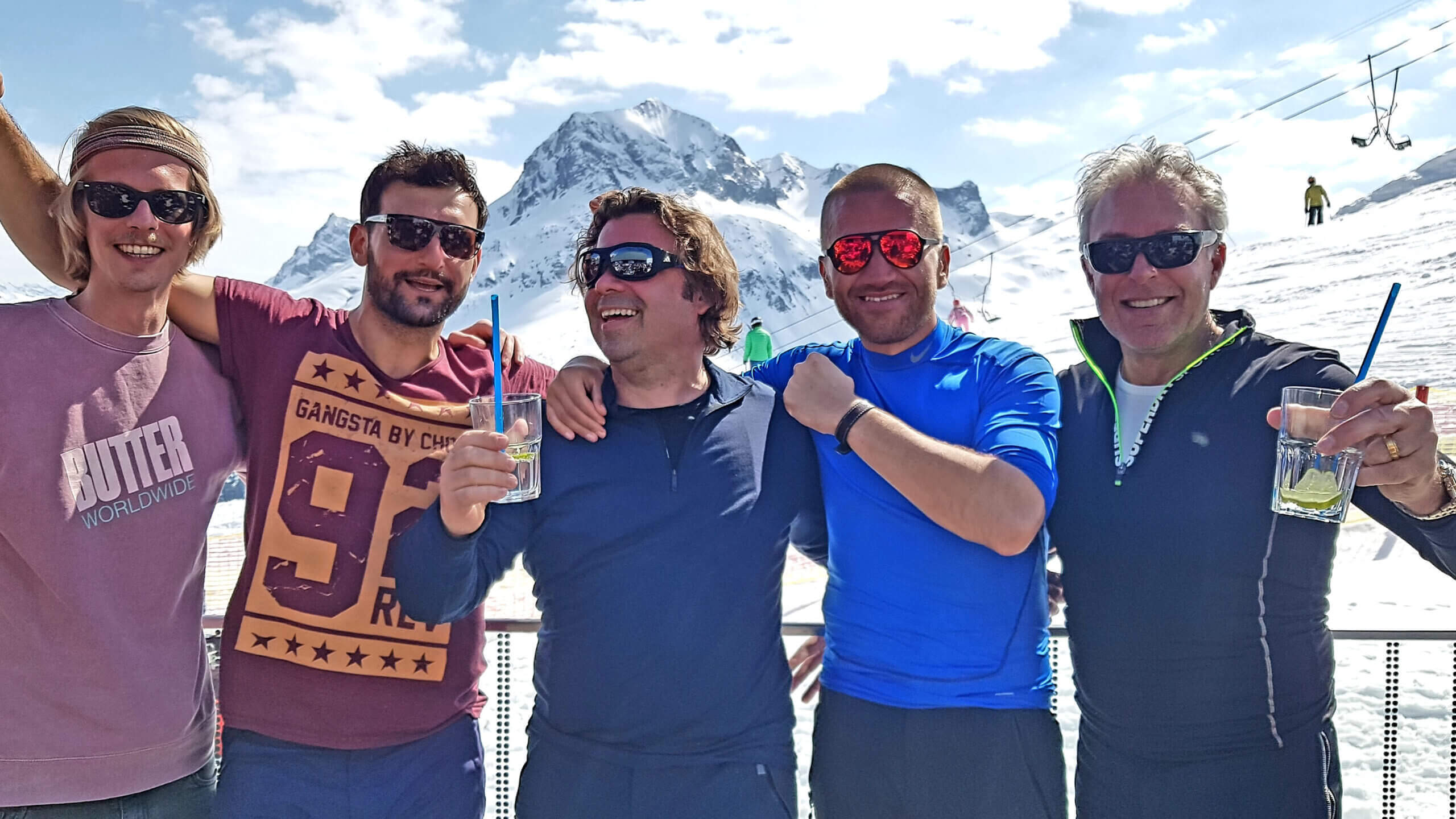 Eine Gruppe Männer mit Getränken in einem Skigebiet in den Bergen