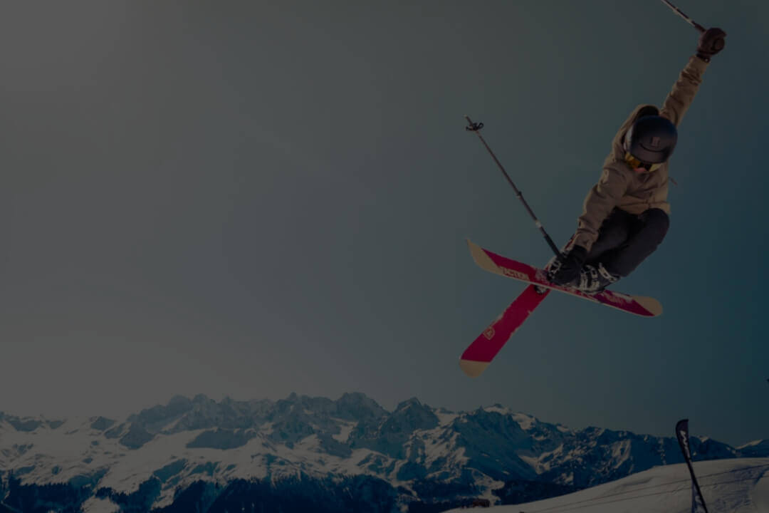 Skifahrerin in den Bergen die einen Trick in der Luft macht