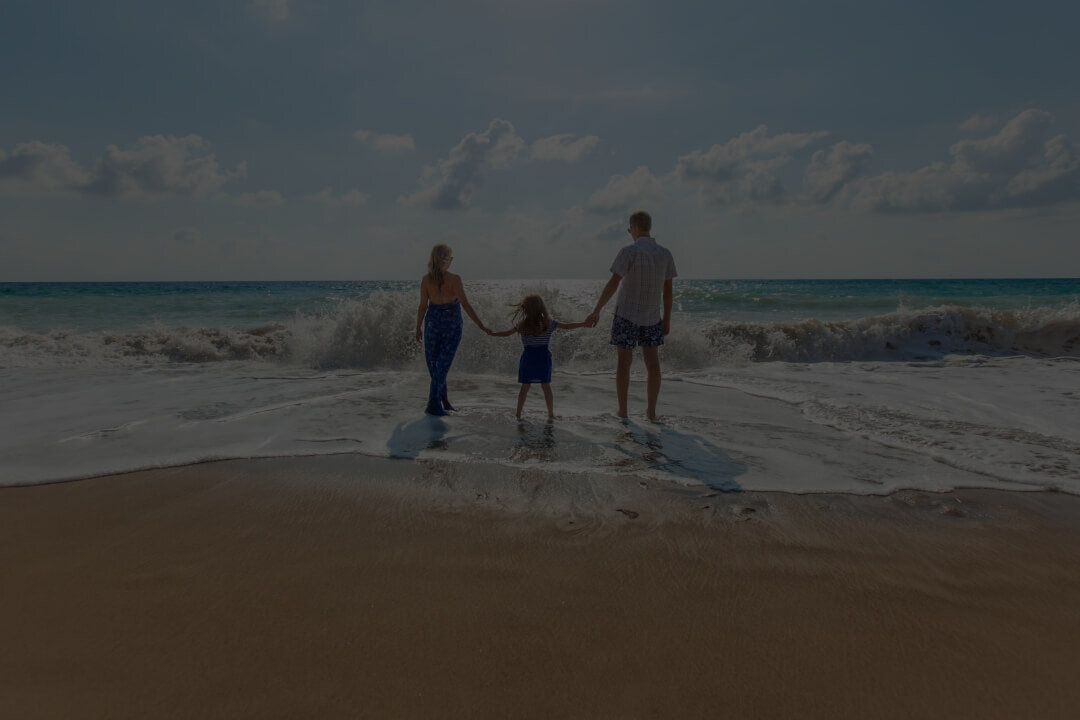Familie mit Kind am Strand mit Wellen