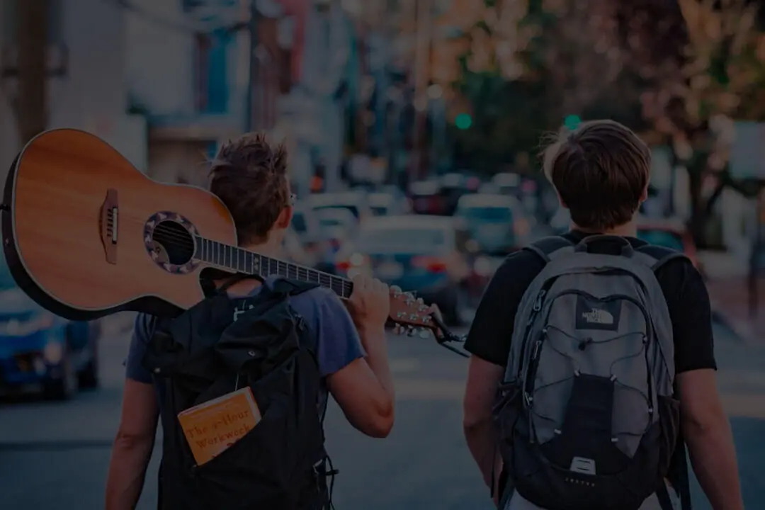 Zwei Männer mit Rucksäcken und einer Gitarre