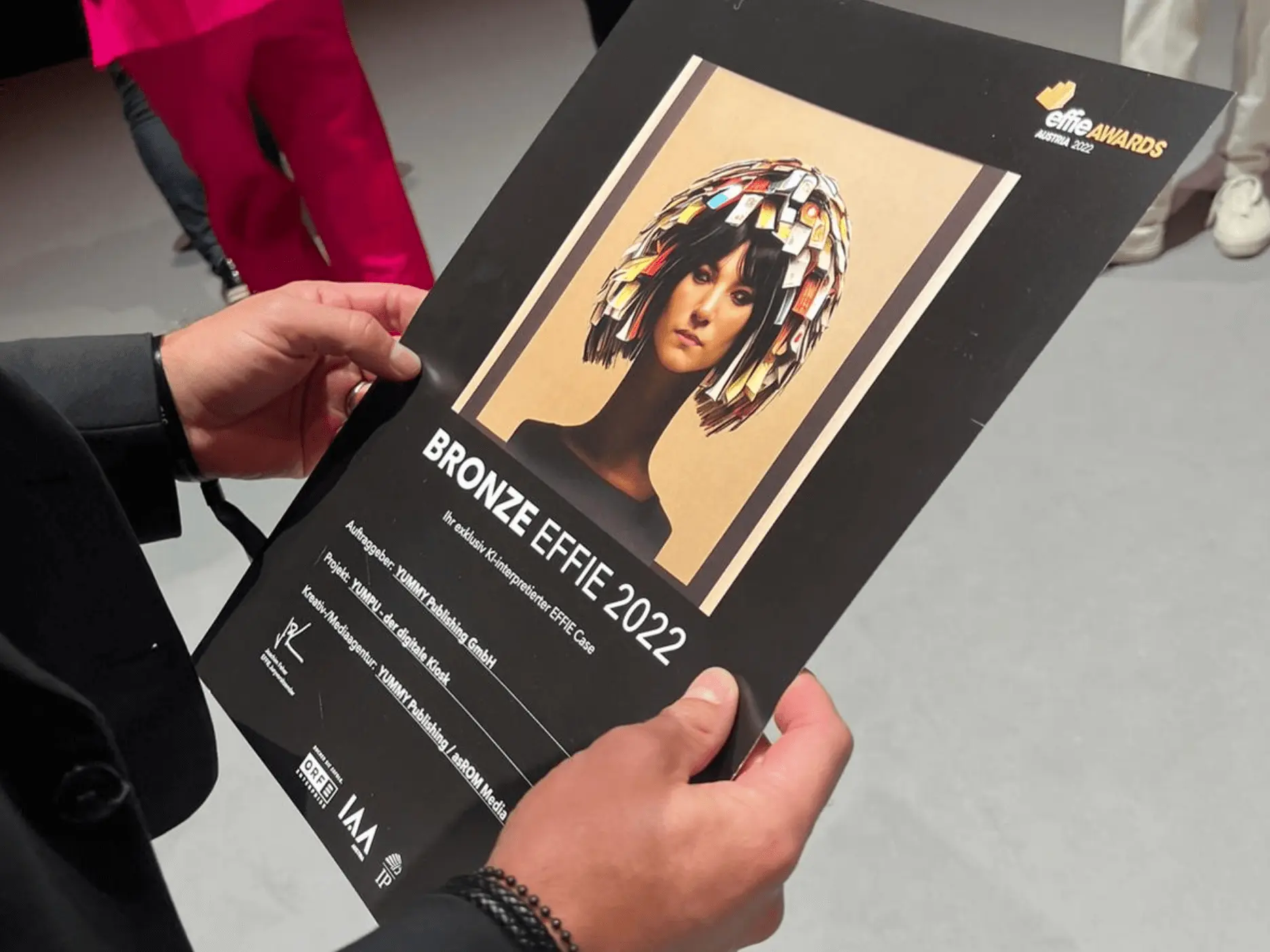 Award Zertifikat mit Bild von einer Frau mit Magazinen in den Haaren und Text - Bronze Effie 2022